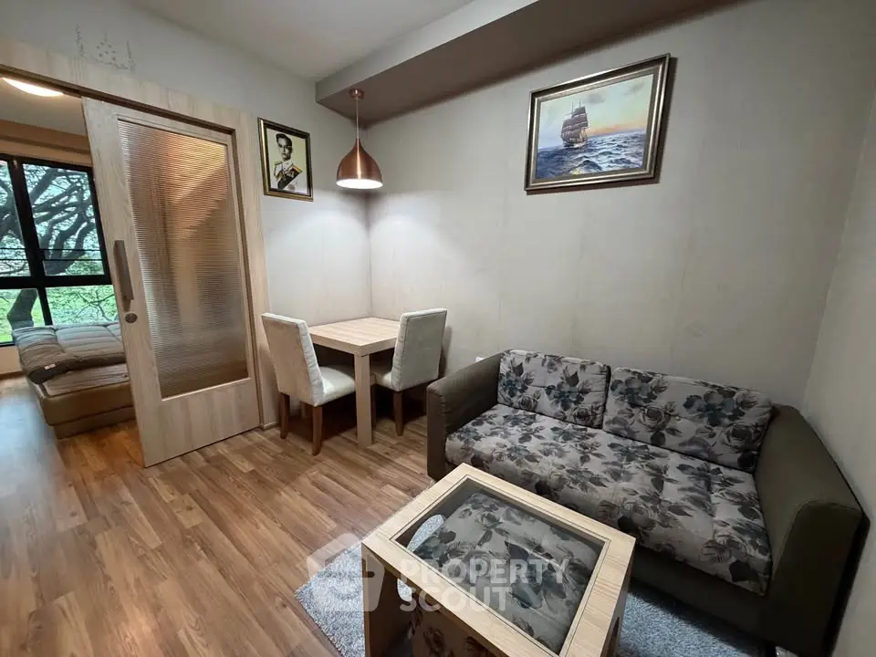 Cozy living room with floral sofa, wooden flooring, and elegant dining area in modern apartment.
