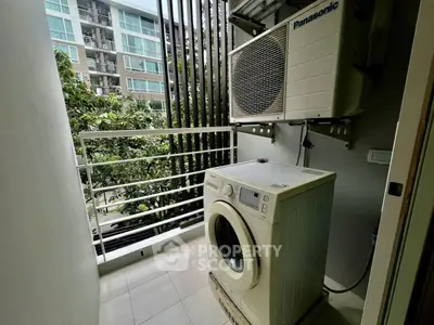 Compact balcony with washing machine and air conditioning unit in modern apartment.