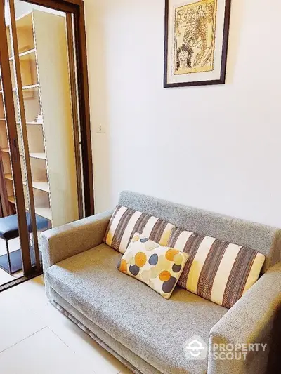 Cozy living space with a stylish grey sofa adorned with chic patterned cushions, complemented by elegant wall art, exuding a warm ambiance.