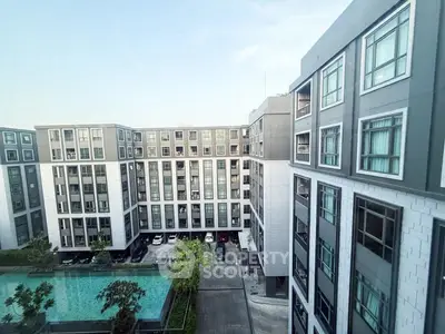 Modern apartment complex with pool and parking, showcasing contemporary architecture and urban living.