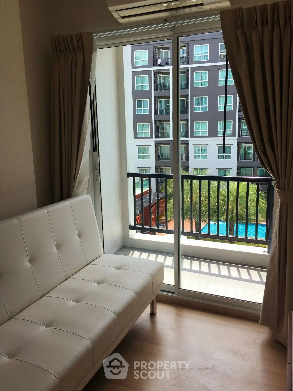 Modern apartment with balcony view overlooking pool and neighboring building.