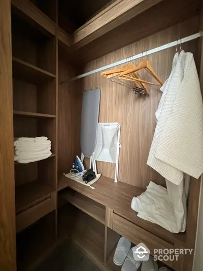 Spacious walk-in closet with wooden shelves and ironing board in modern home.