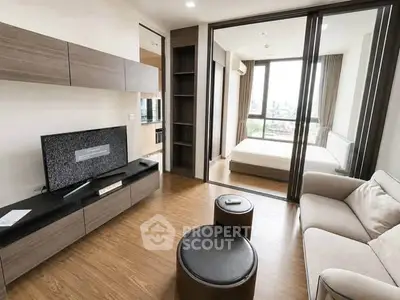 Modern apartment living room with wooden flooring and sliding glass doors to bedroom.