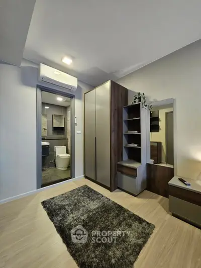 Modern bedroom with ensuite bathroom, featuring sleek wardrobe and air conditioning unit.
