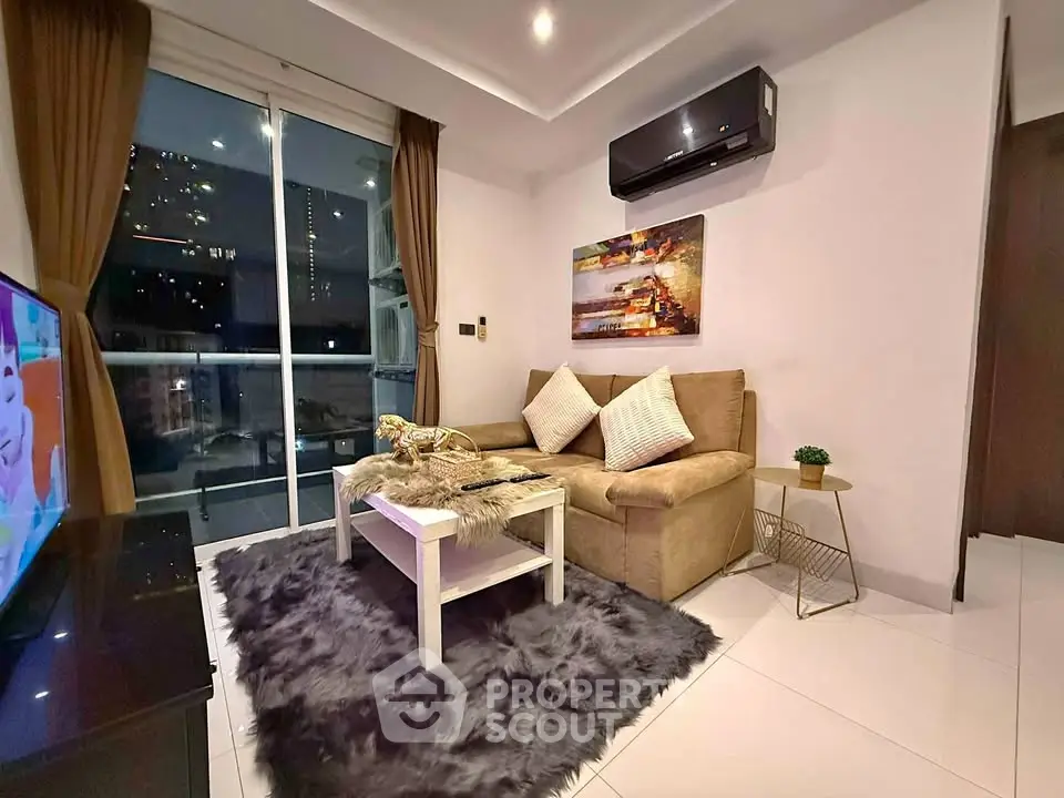 Cozy modern living room with plush sofa, stylish decor, and city view balcony.
