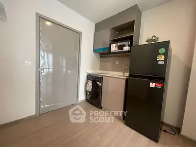 Modern compact kitchen with fridge and washing machine in sleek apartment.