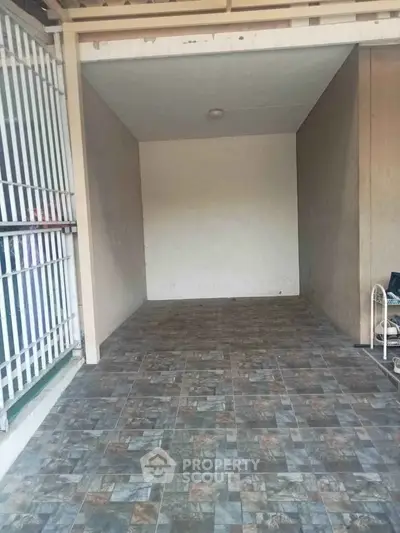 Spacious tiled garage or storage area with gated entrance, ideal for secure parking or extra storage.