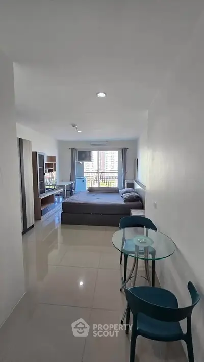 Modern studio apartment with sleek furnishings and city view, featuring a cozy bed and stylish dining area.