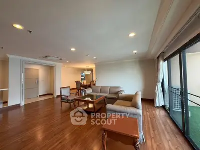 Spacious living room with elegant wooden flooring and large windows offering natural light.