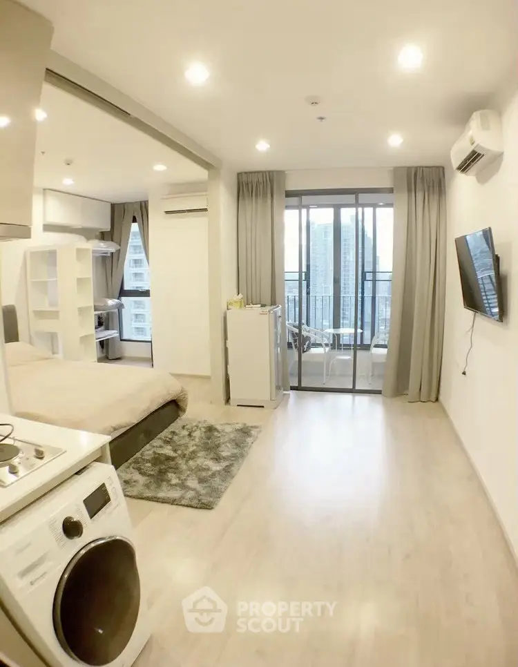 Modern studio apartment with open layout, featuring a cozy living area, compact kitchen, and balcony with city view.
