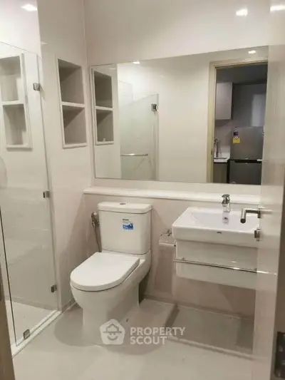 Modern bathroom with glass shower and sleek fixtures in contemporary apartment.