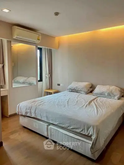 Spacious bedroom with modern design and natural lighting, featuring a comfortable bed and stylish decor.