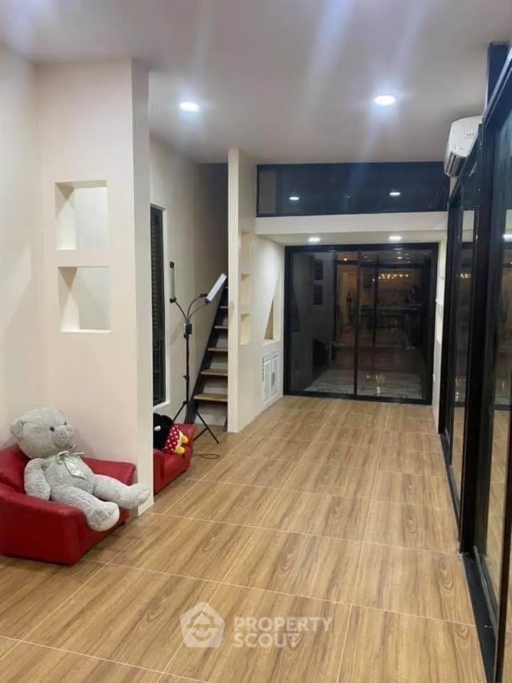 Spacious modern interior with wooden flooring and glass doors, perfect for versatile living space.