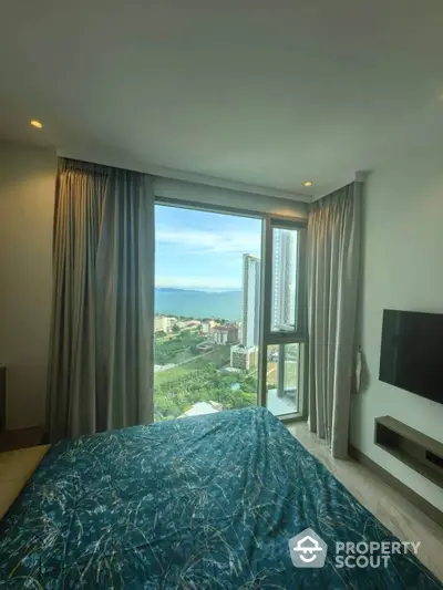 Luxurious bedroom with stunning city and sea view from large window, modern decor and TV.