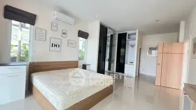 Spacious bedroom with modern design and ample natural light, featuring built-in wardrobes and sleek flooring.