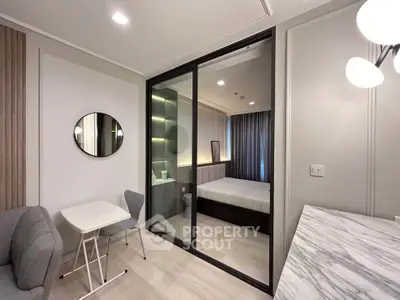 Modern studio apartment with glass partition, cozy living area, and stylish decor.
