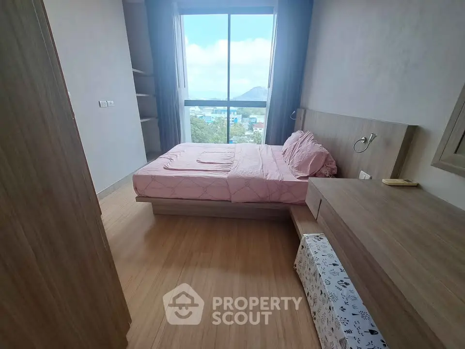 Modern bedroom with large window and scenic view, featuring stylish wooden furniture and cozy ambiance.