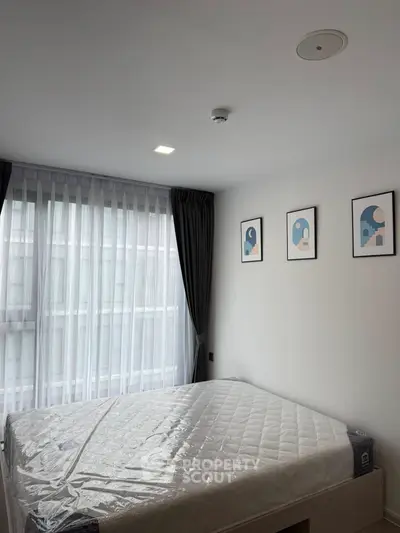 Modern bedroom with large window and stylish decor in a contemporary apartment.