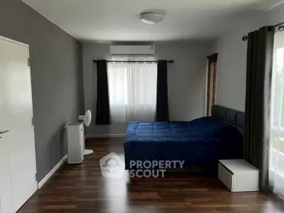 Spacious bedroom with modern decor and large window for natural light.