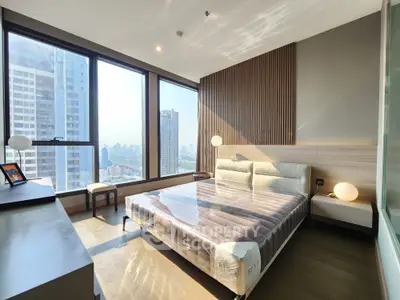 Luxurious bedroom with floor-to-ceiling windows offering stunning city views and modern furnishings.