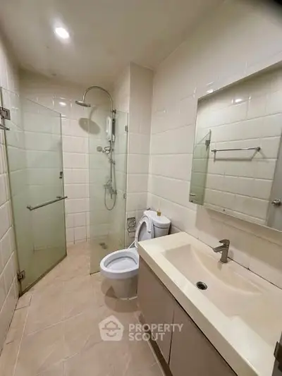 Modern bathroom with glass shower and sleek fixtures in a contemporary apartment.