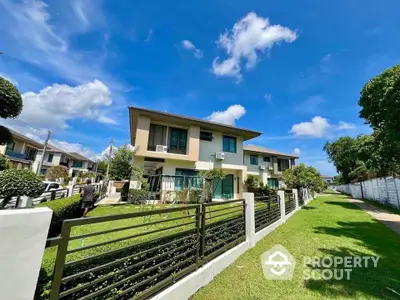 Modern two-story house with lush garden and clear blue sky, perfect for family living.