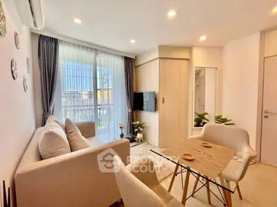 Modern living room with cozy sofa and glass dining table, bright natural light.