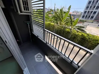 Spacious balcony with lush greenery view in modern urban setting.