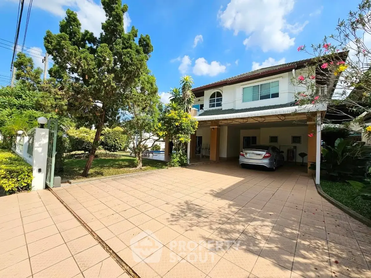 Charming two-story house with spacious driveway and lush garden under a clear blue sky.