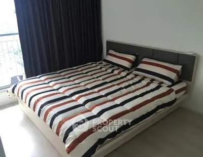 Modern bedroom with stylish striped bedding and large window for natural light.
