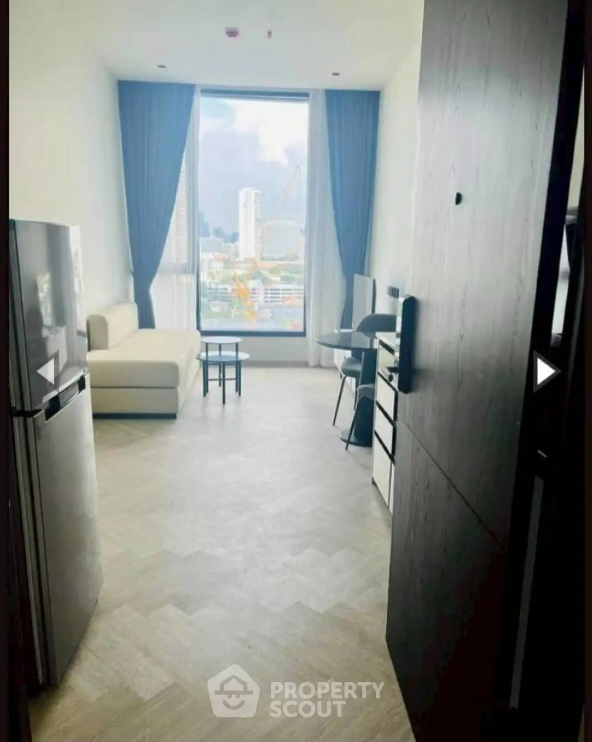 Modern living room with city view, featuring sleek furniture and large windows for natural light.