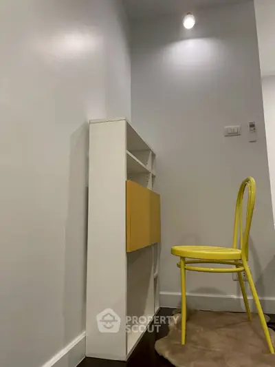Modern minimalist study corner with yellow chair and white shelving unit.