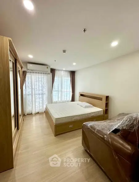 Spacious bedroom with modern furnishings and large windows for natural light.