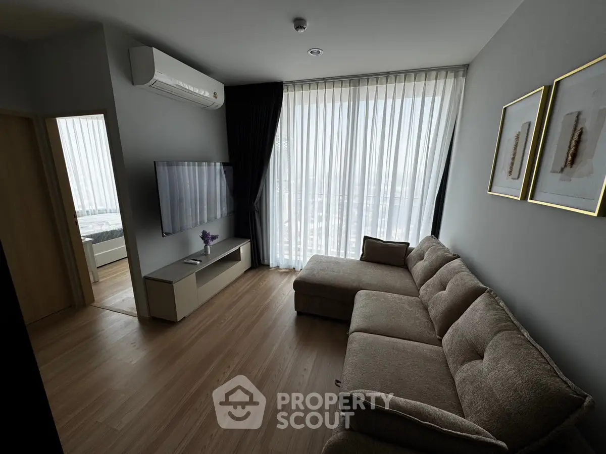 Modern living room with large windows and stylish furniture in a high-rise apartment.