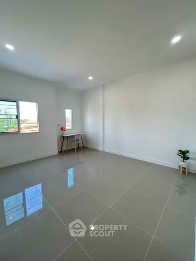 Spacious empty room with glossy tiled floor and bright natural light.