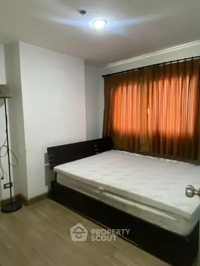 Cozy bedroom with wooden flooring and warm lighting, perfect for relaxation.