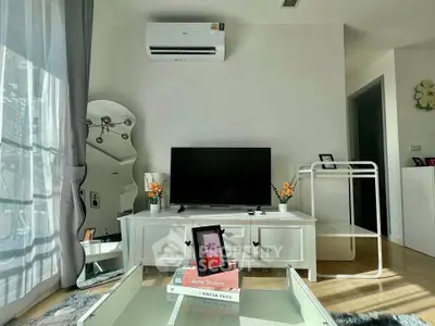 Modern living room with stylish decor, featuring a TV, air conditioning, and natural light through large windows.