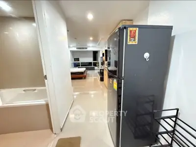 Modern apartment interior with sleek kitchen and cozy living area, featuring a stylish fridge and bathtub.