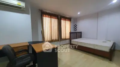 Spacious bedroom with natural light, featuring a bed, desk, and chair, ideal for comfortable living.