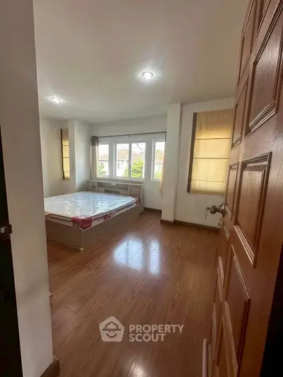 Spacious bedroom with large windows and wooden flooring