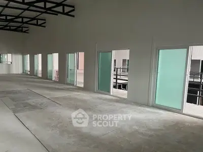 Spacious industrial warehouse interior with large windows and high ceilings