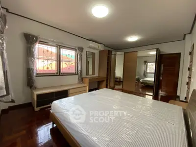 Spacious bedroom with modern furnishings and large windows for natural light.