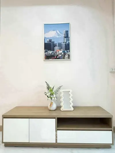Modern minimalist living room with stylish wooden cabinet and decorative vase, featuring a framed cityscape artwork.