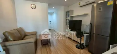Modern living room with sleek furniture and stainless steel fridge in a cozy apartment.
