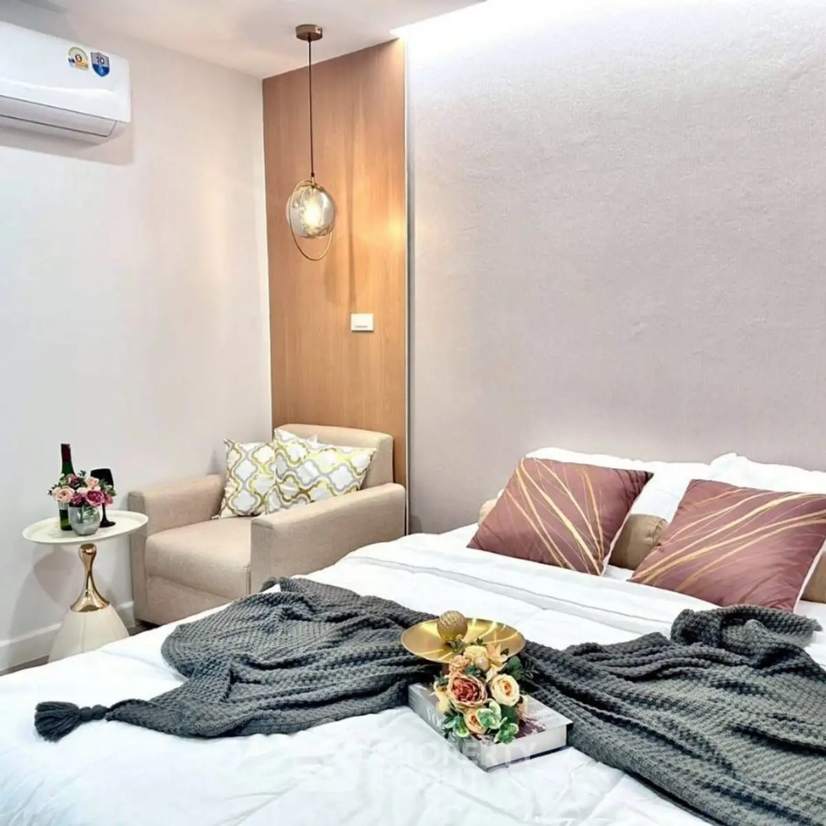 Cozy bedroom with modern decor and elegant lighting, featuring a comfortable armchair and stylish bedding.