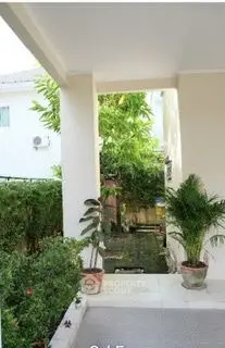 Charming garden entrance with lush greenery and potted plants, perfect for relaxation.
