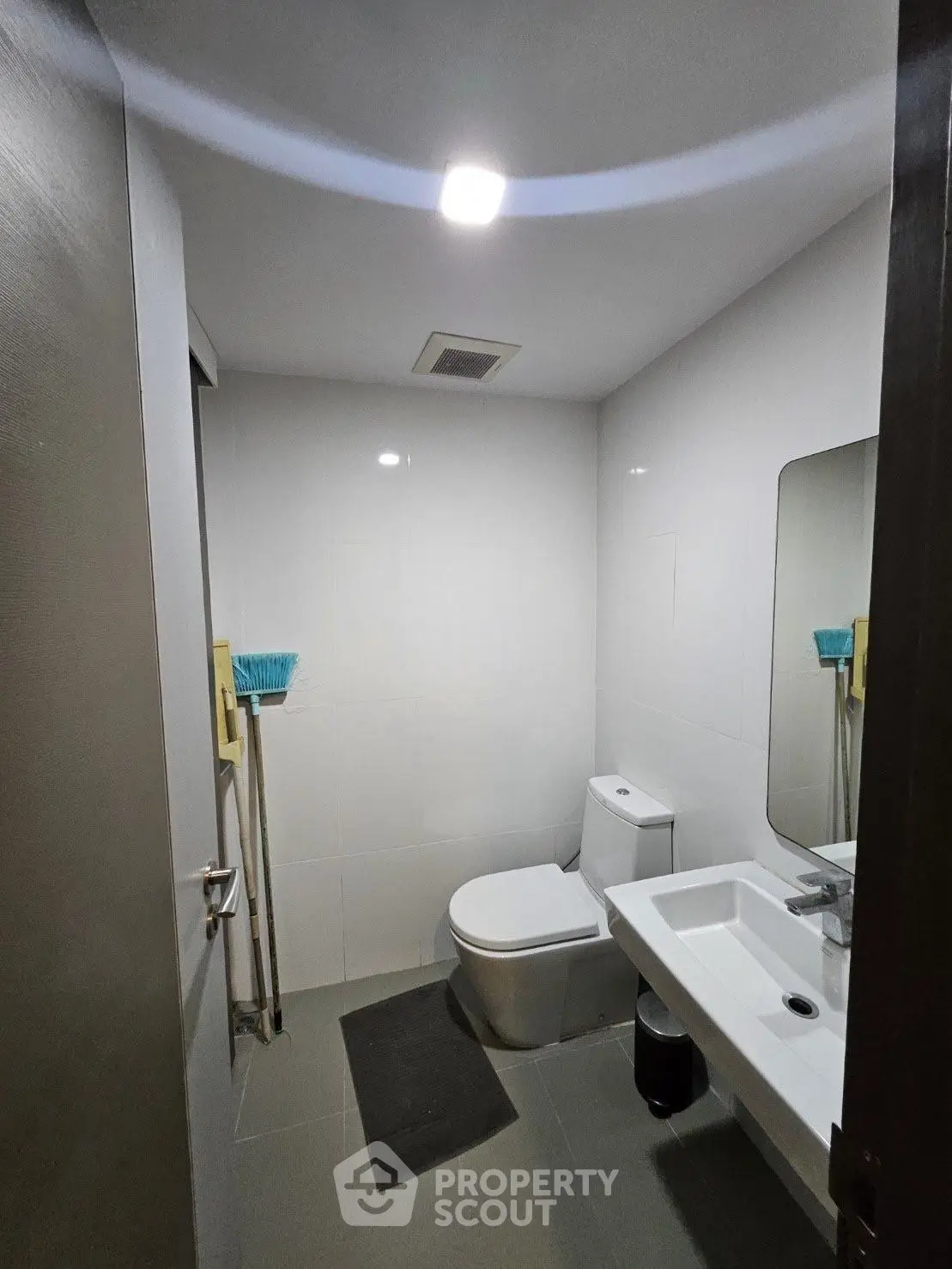 Modern bathroom with sleek fixtures and minimalist design, featuring a toilet, sink, and mirror.