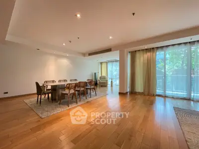 Spacious open-plan living and dining area with wooden flooring and large windows.