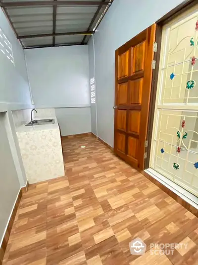 Charming utility area with wooden door and decorative glass, featuring a compact sink and tiled flooring.