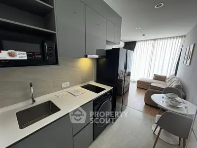 Modern open-layout kitchen with sleek appliances and cozy living area in stylish apartment.